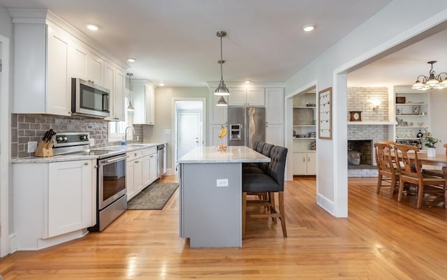 kitchen with appliances with stainless steel finishes, a breakfast bar area, white cabinetry, and a sink