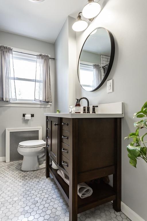 bathroom with baseboards, a wealth of natural light, toilet, and vanity