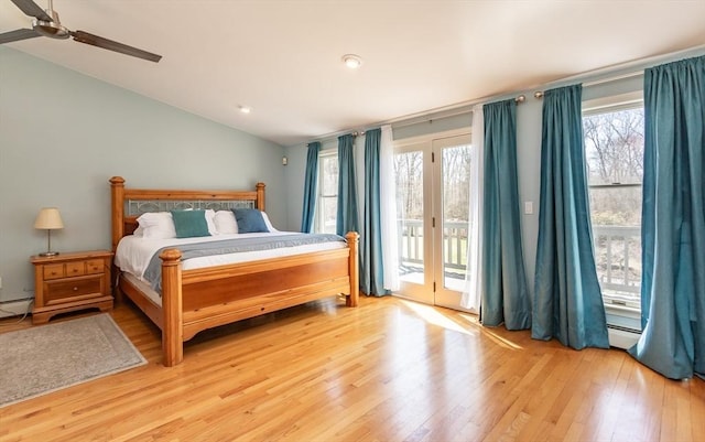 bedroom with multiple windows, access to outside, lofted ceiling, and light wood-style floors