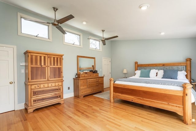 bedroom featuring light wood finished floors, a ceiling fan, a towering ceiling, and baseboards