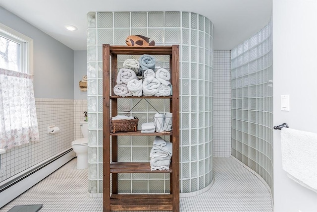 bathroom with a baseboard radiator, toilet, tile walls, tile patterned floors, and a walk in shower
