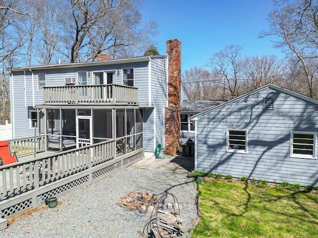 rear view of house featuring a chimney, a balcony, and a sunroom