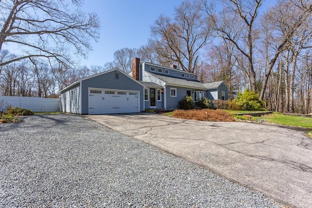 view of front of home with concrete driveway, a chimney, a garage, and fence