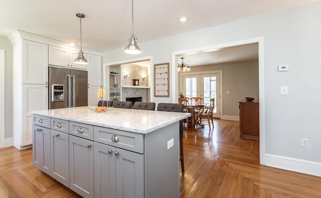 kitchen featuring a fireplace, gray cabinetry, high end fridge, and baseboards