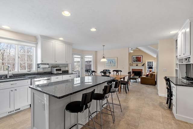 kitchen with pendant lighting, sink, a breakfast bar, a center island, and white cabinets