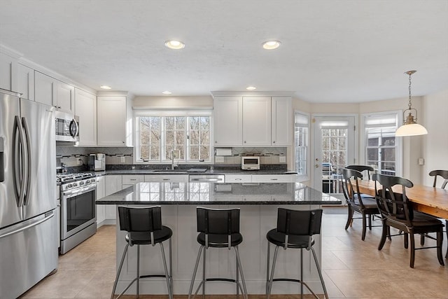 kitchen featuring pendant lighting, white cabinetry, sink, a center island, and stainless steel appliances