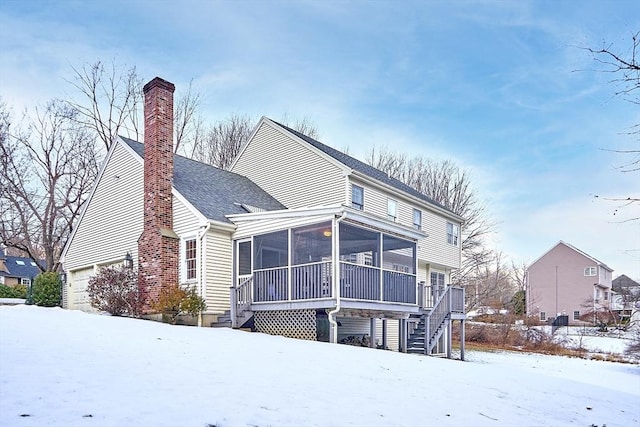 snow covered property featuring a garage and a sunroom