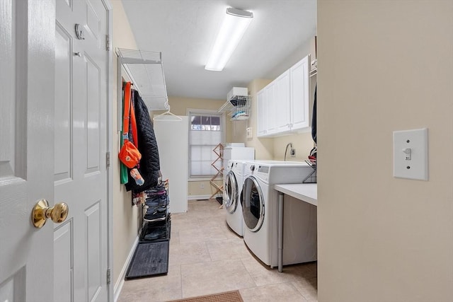 clothes washing area with cabinets, light tile patterned floors, and washing machine and clothes dryer