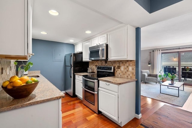 kitchen featuring tasteful backsplash, appliances with stainless steel finishes, light hardwood / wood-style floors, and white cabinets