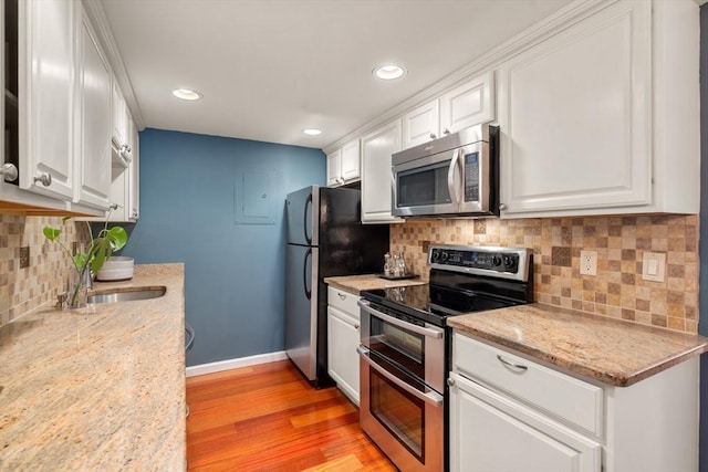 kitchen with stainless steel appliances, white cabinetry, and light stone counters