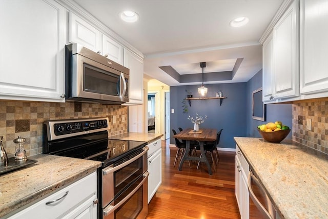 kitchen featuring decorative light fixtures, white cabinets, and appliances with stainless steel finishes