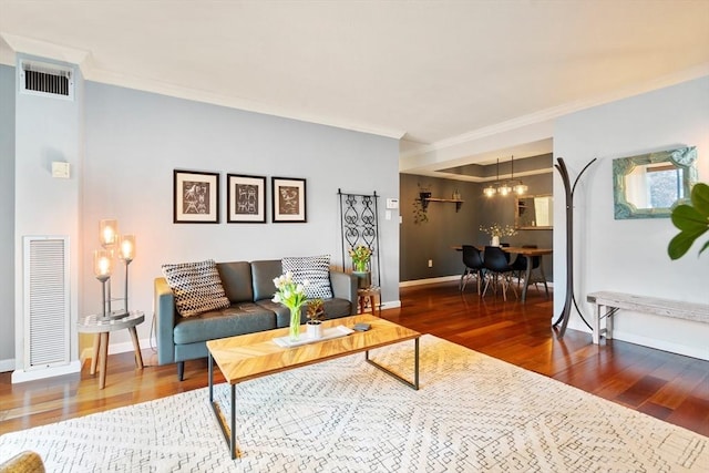 living room with a notable chandelier, crown molding, and wood-type flooring