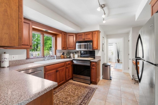kitchen featuring a sink, brown cabinets, plenty of natural light, and appliances with stainless steel finishes