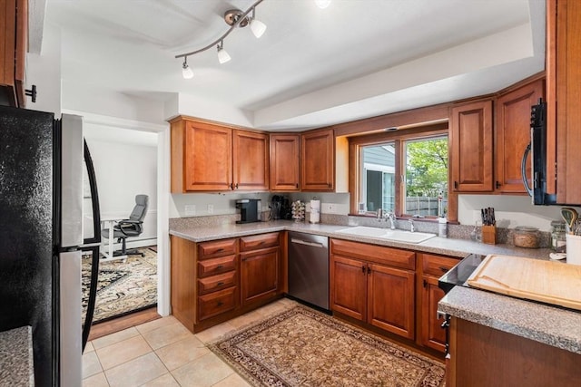 kitchen with stainless steel appliances, light tile patterned flooring, a sink, brown cabinets, and light countertops