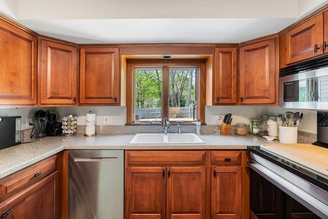 kitchen with a sink, stainless steel appliances, light countertops, and brown cabinets