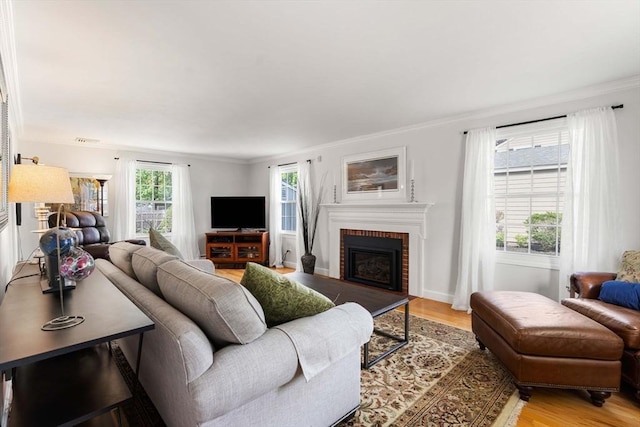 living area featuring a fireplace, light wood-style flooring, crown molding, and visible vents