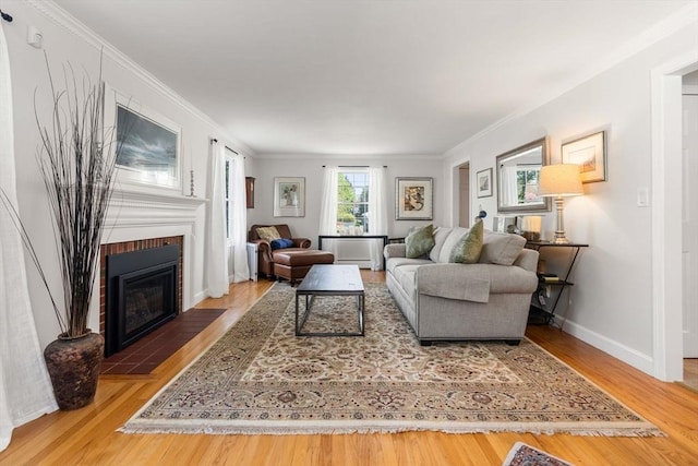 living area with crown molding, wood finished floors, a fireplace, and baseboards