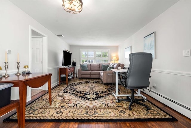 living room featuring baseboard heating, visible vents, and wood finished floors