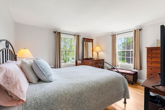 bedroom featuring baseboards, light wood-type flooring, and multiple windows