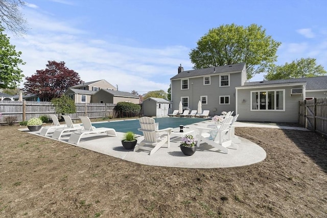 back of property featuring a chimney, an outbuilding, a patio, a fenced backyard, and a storage unit