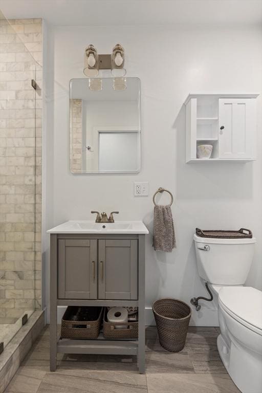 full bath with vanity, wood finished floors, a shower stall, and toilet