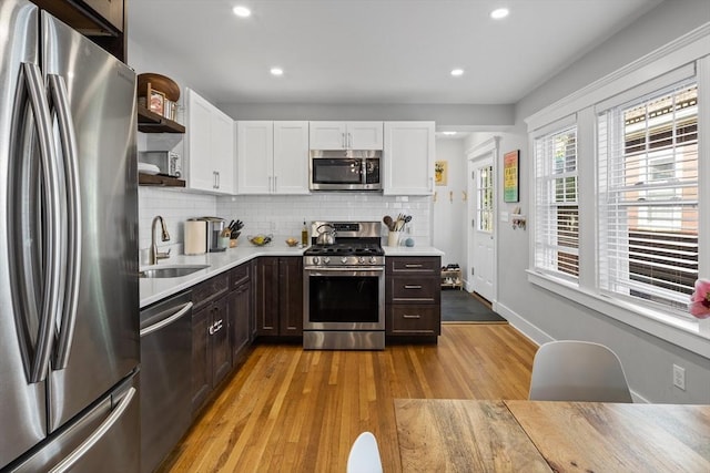 kitchen featuring open shelves, light countertops, appliances with stainless steel finishes, white cabinetry, and a sink