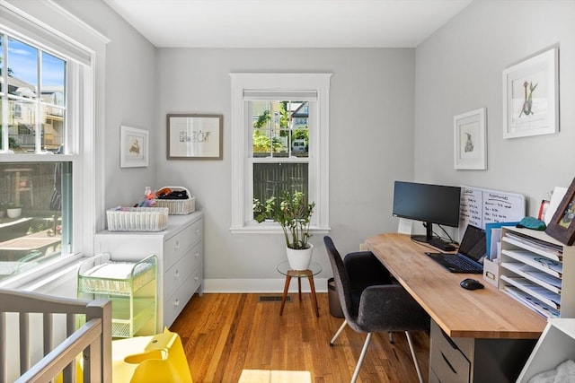 home office featuring visible vents, wood finished floors, a wealth of natural light, and baseboards