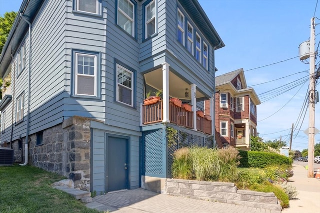 view of side of property with stone siding and central AC unit