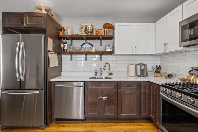 kitchen featuring decorative backsplash, stainless steel appliances, light countertops, white cabinetry, and a sink