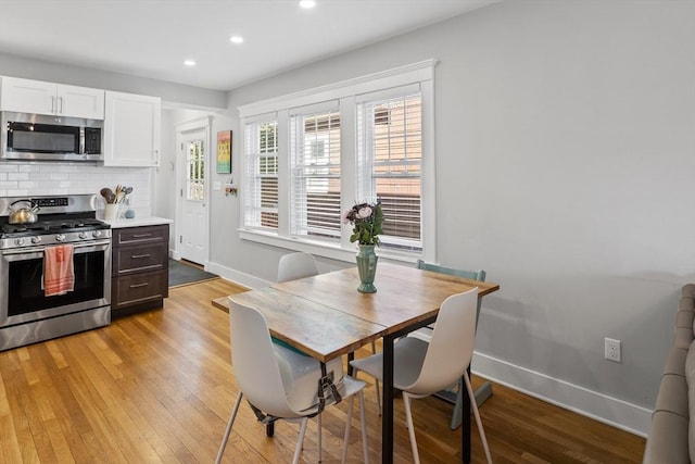 kitchen featuring appliances with stainless steel finishes, light wood-type flooring, backsplash, and baseboards