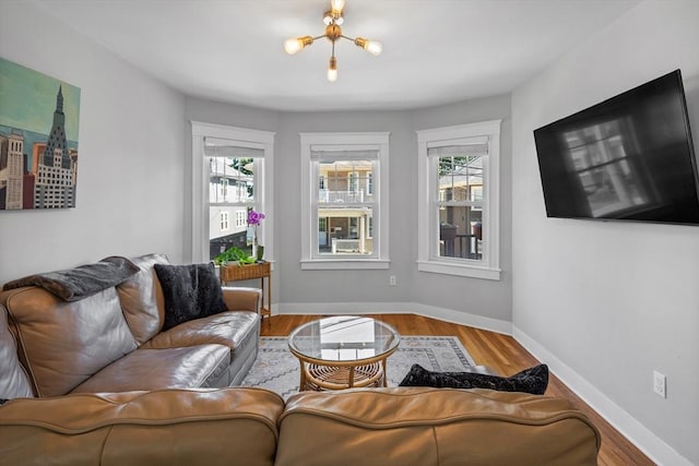 living room with baseboards, an inviting chandelier, wood finished floors, and a healthy amount of sunlight