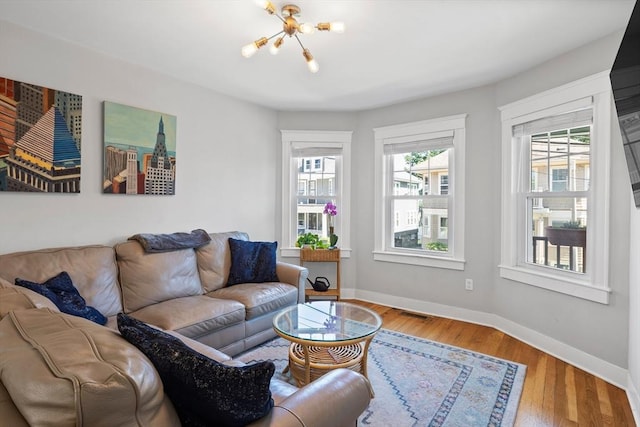 living area with plenty of natural light, baseboards, a chandelier, and wood finished floors