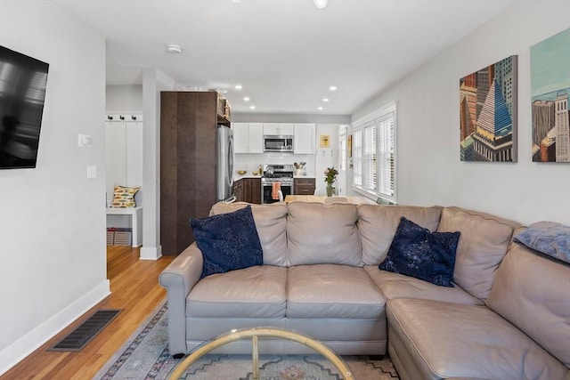 living area featuring recessed lighting, baseboards, visible vents, and light wood finished floors