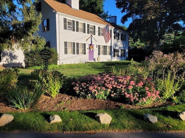 colonial house featuring a chimney and a front lawn