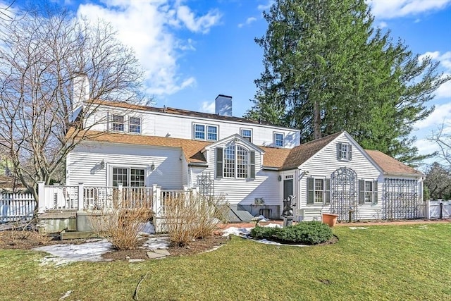 rear view of property with a wooden deck, a chimney, fence, and a yard