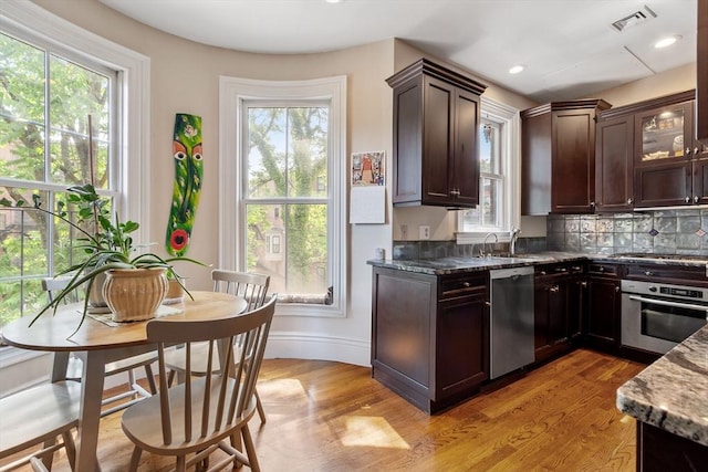 38 Concord Sq Unit 2, Boston, MA 02118 - kitchen with stainless steel appliances, dark stone counters, dark brown cabinetry, light wood finished floors, and backsplash
