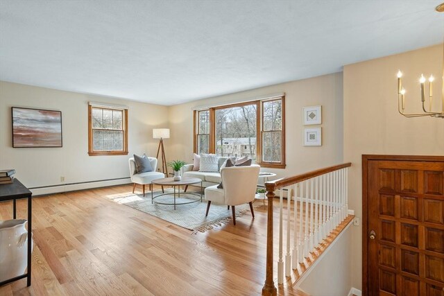 living area featuring an inviting chandelier, wood finished floors, and a baseboard radiator