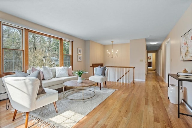 living room with baseboards, an inviting chandelier, and light wood finished floors