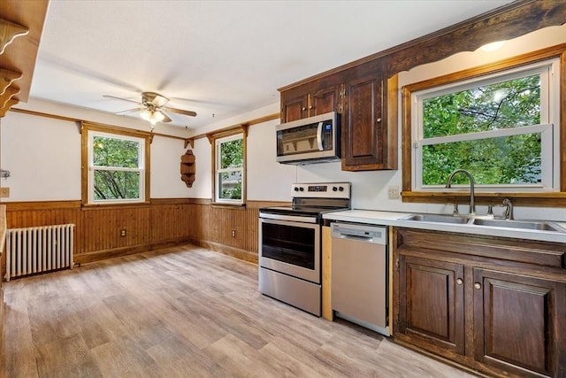 61 Mattawa Cir, Orange, MA 01364 - kitchen featuring radiator heating unit, appliances with stainless steel finishes, wainscoting, light wood-style floors, and a ceiling fan