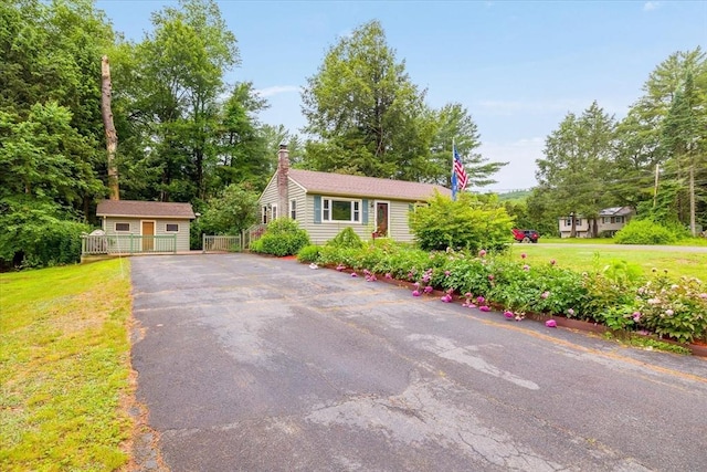 61 Mattawa Cir, Orange, MA 01364 - view of front facade featuring asphalt driveway, an outdoor structure, a front yard, and a chimney