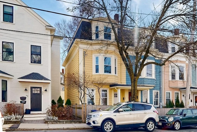 view of front facade featuring mansard roof and fence