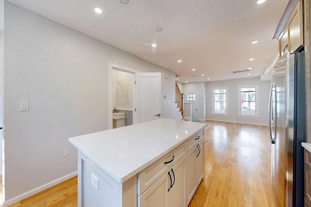 kitchen with a center island, baseboards, recessed lighting, freestanding refrigerator, and light wood-style floors