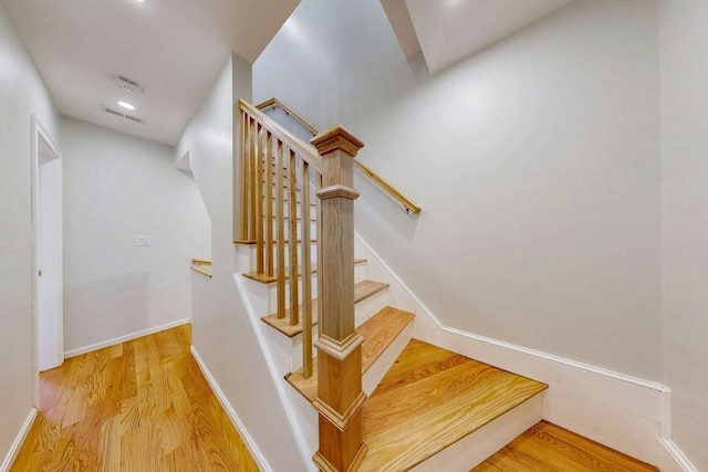 staircase with wood finished floors, visible vents, and baseboards