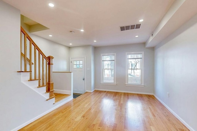 entrance foyer with stairs, wood finished floors, visible vents, and baseboards