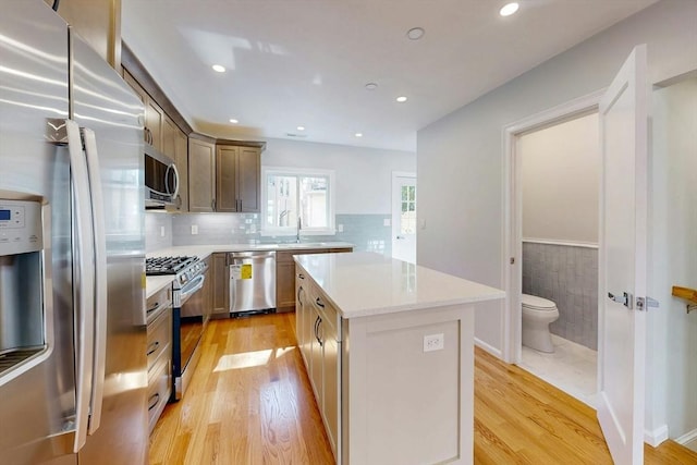 kitchen with a kitchen island, light wood-style flooring, stainless steel appliances, and a sink