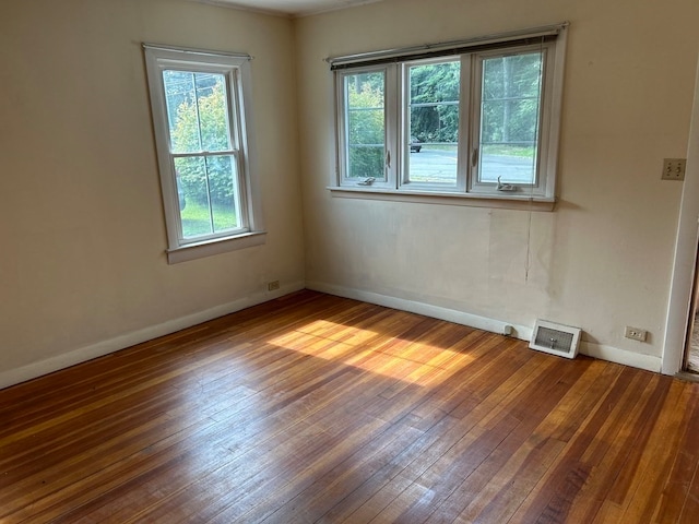 empty room with plenty of natural light and hardwood / wood-style flooring