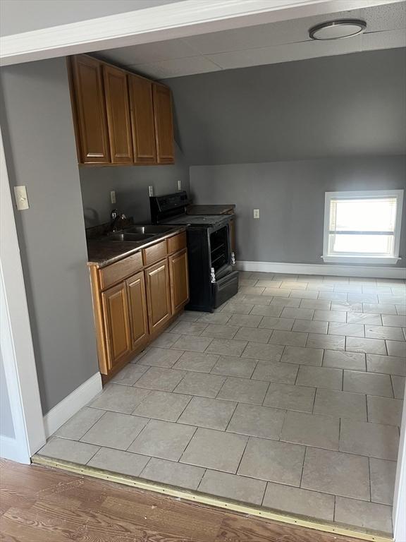 422 County St, Fall River, MA 02723 - kitchen with black range, lofted ceiling, baseboards, dark countertops, and a sink
