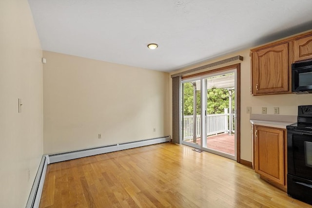 71 Johnny Appleseed Ln, Leominster, MA 01453 - kitchen with black appliances, light countertops, light wood-style floors, and a baseboard heating unit