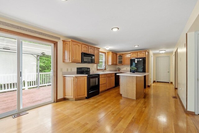 71 Johnny Appleseed Ln, Leominster, MA 01453 - kitchen featuring black appliances, light countertops, light wood-style floors, a sink, and a center island