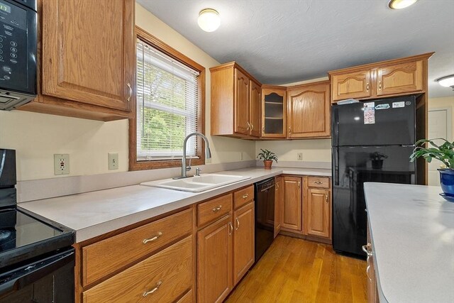 71 Johnny Appleseed Ln, Leominster, MA 01453 - kitchen with a sink, black appliances, light wood-style flooring, and light countertops